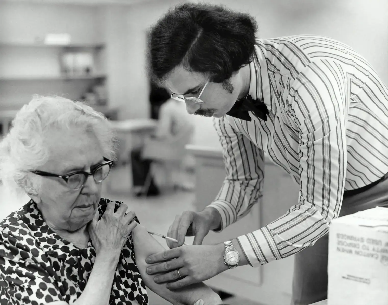 Photo by CDC - AssistedKin grayscale photography of man holding syringe injecting on woman left arm