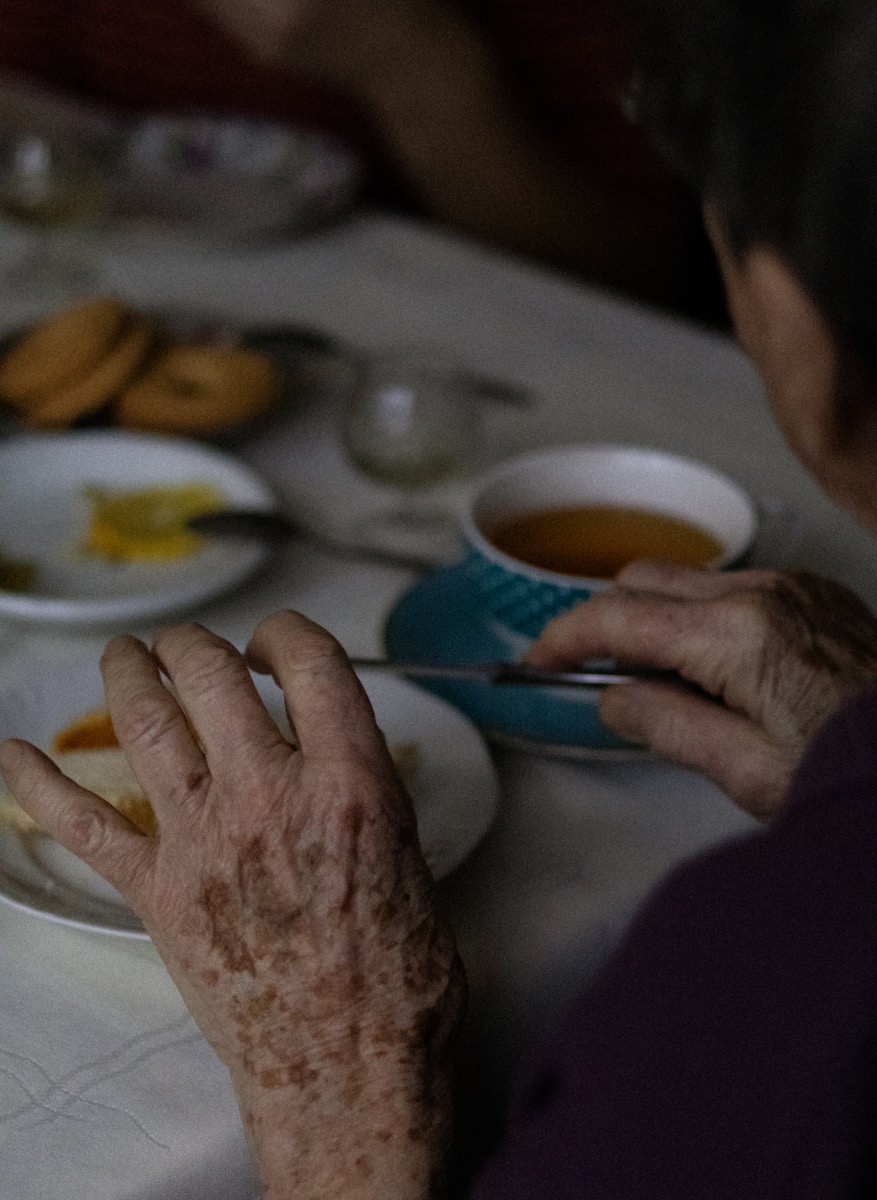 an older woman sitting at a table with plates of food